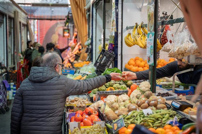 Archivo - Un hombre en un puesto del mercado de abastos realiza sus compras, en Sevilla (Andalucía, España).