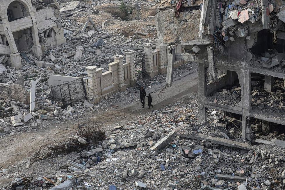 Palestinos caminan entre edificios en ruinas en la ciudad de Gaza por la ofensiva militar de Israel contra la Franja, en medio del alto el fuego entre Israel y Hamás (archivo)