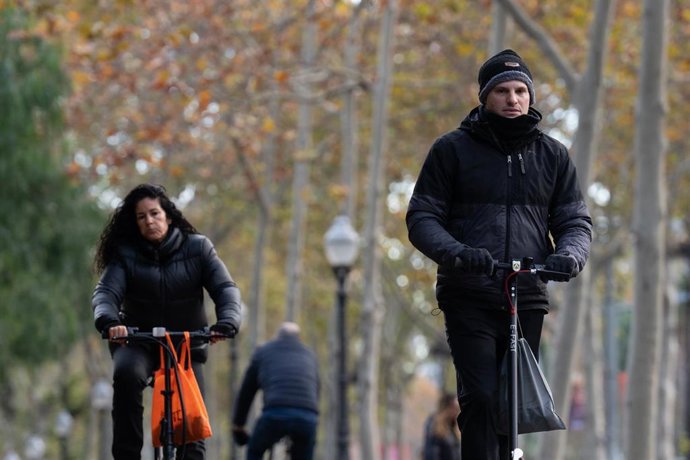 Archivo - Una mujer monta en bicicleta y un hombre en patinete eléctrico.