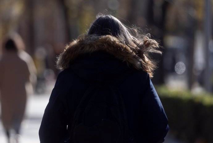 Una mujer abrigada pasea.