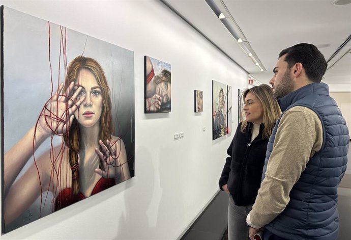 La artista Virginia Villar y el diputado Roberto Migallón observan una de las obras de la exposición 'Paisajes habitados', que se puede visitar en el Teatro Zorrilla.