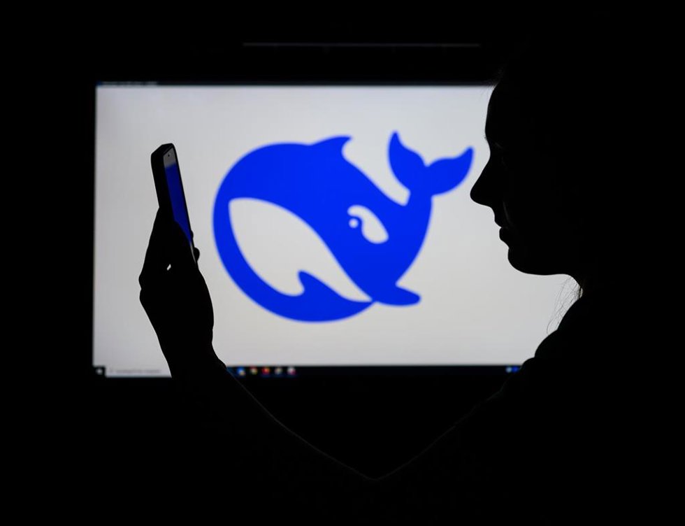 28 January 2025, Brandenburg, Sieversdorf: The logo of Chinese AI start-up DeepSeek can be seen on a computer screen, while a woman looks at her smartphone in front of it.
