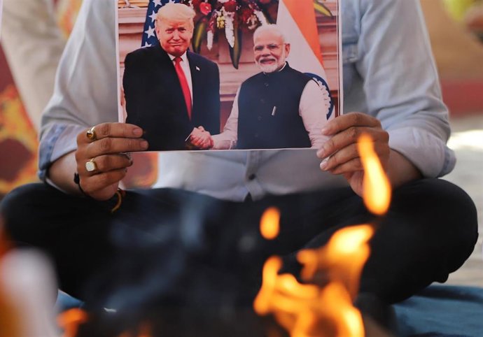 Archivo - Un activista sujeta una fotografía de Donald Trump y Narendra Modi 