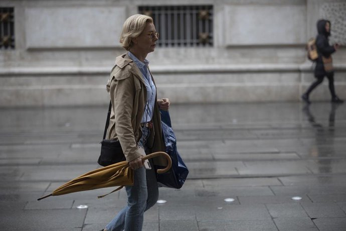 Archivo - Una mujer con gabardina y paraguas. A 21 de octubre de 2022, en Sevilla (Andalucía, España).