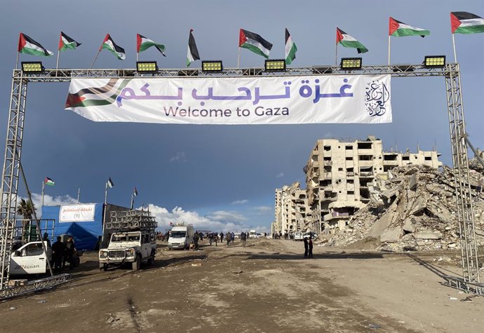 January 26, 2025, Gaza City, Gaza Strip, Palestinian Territory: People gather by a banner welcoming people near the rubble of a collapsed building along Gaza's coastal al-Rashid Street for people to cross from the Israeli-blocked Netzarim corridor from th