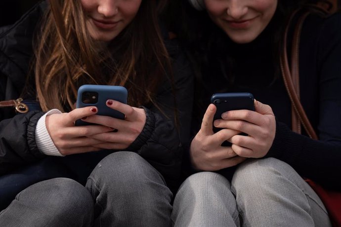 Imagen de archivo - Dos personas usan el teléfono móvil en Barcelona