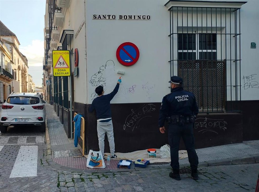 Un grafitero de 18 años tapando con pintura las pintadas realizadas en la fachada de un colegio de El Puerto.