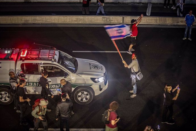 Archivo - November 6, 2024, Tel Aviv, Israel: An Israeli protestor waves a National flag as he faces a police car, during a spontaneous demonstration after the Israeli Prime Minister Benjamin Netanyahu fired Defense Minster Yoav Gallant. On Tuesday Benjam