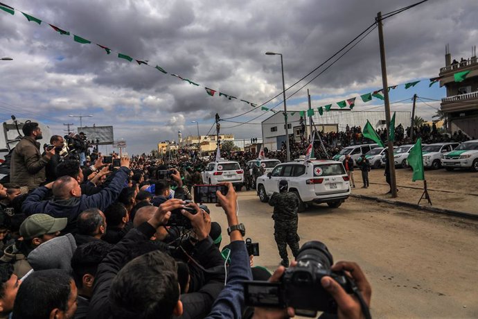 08 February 2025, Palestinian Territories, Deir al-Balah: Israeli hostages get delivered to representatives of the International Committee of the Red Cross (ICRC) by fighters of the Ezz al-Din Al-Qassam brigades, the military wing of Hamas, in the fifth b