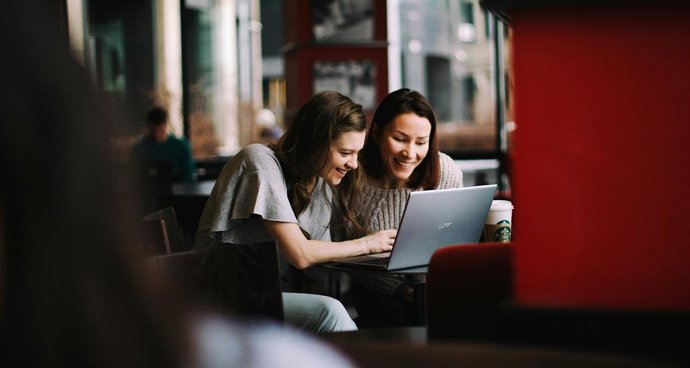 Duas mulheres olhando para algo em uma tela de computador