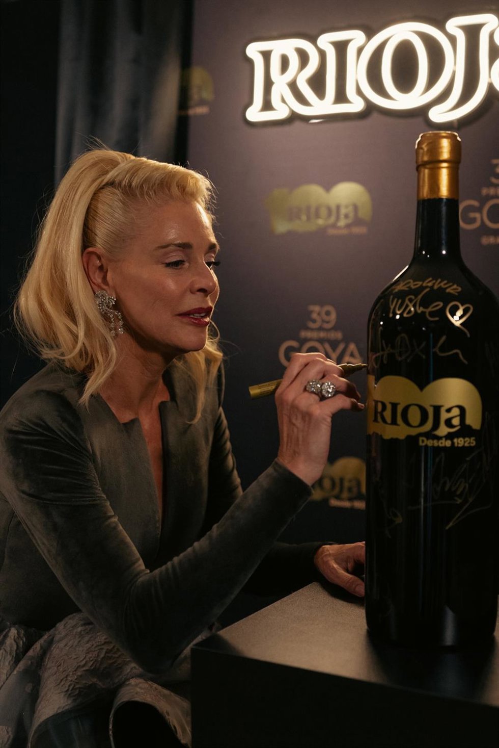 La actriz Belén Rueda firma una de las botellas especiales de Rioja del centenario que han desaparecido tras los Goya