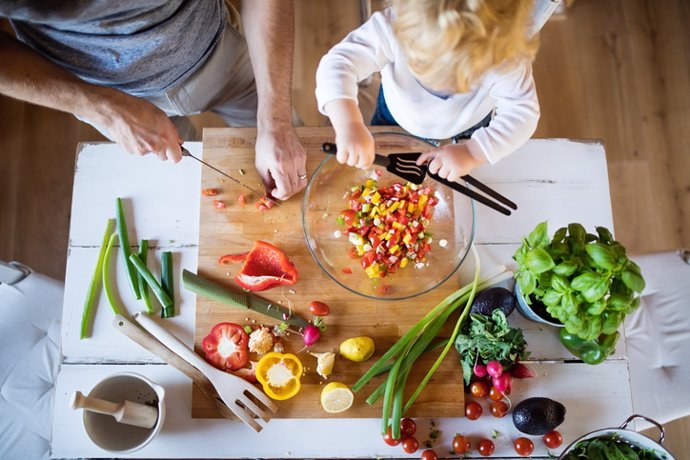 Archivo - Imagen de archivo de padre e hijo cortando verduras.