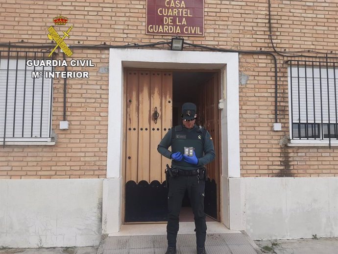 Un agente de la Guardia Civil con las pastillas de hachís incautadas a un hombre que las pasaba junto al muro de un instituto de Alcalá del Valle.