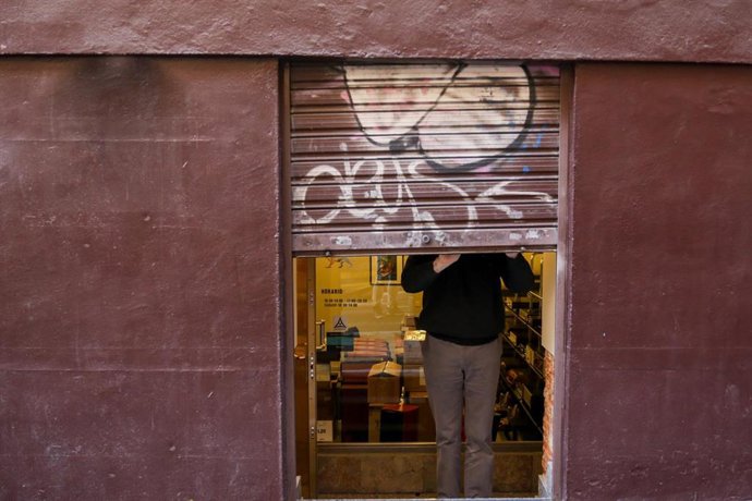 Archivo - Un pequeño empresario cerrando su negocio tras su jornada laboral