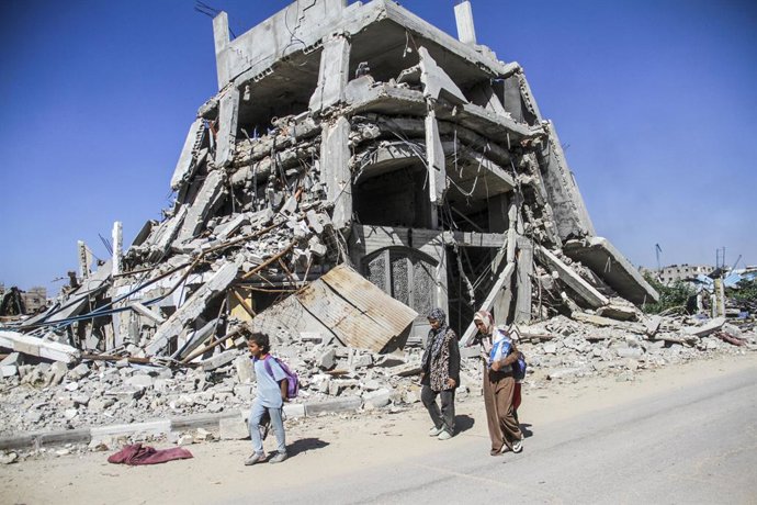 Archivo - Arquivo - Palestinos ao lado de um prédio destruído por ataques do exército israelense em Jabalia, no norte da Faixa de Gaza (arquivo).