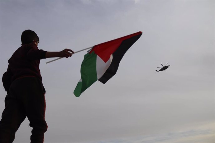 Archivo - 14 March 2021, Palestinian Territories, Hebron: A child waves the Palestinian flag as an Israeli army helicopter carrying Israeli Prime Minister Benjamin Netanyahu flies over the heritage site of ancient Susya, in the West Bank village of Susya.