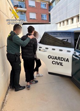 Agentes de la Guardia Civil conducen a dos de los detenidos a un vehículo tras su detención