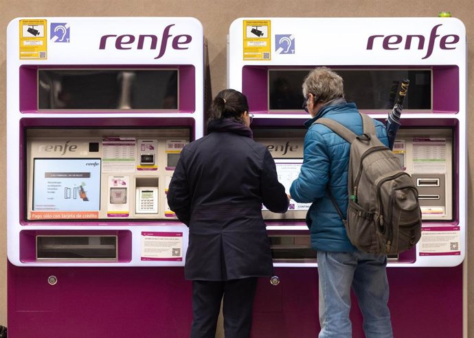 Varias personas compran billetes en una máquina de Renfe
