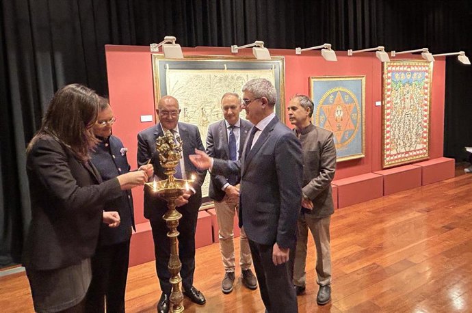 Las autoridades presentes en la inauguración de la exposición sobre arte espiritual de la India encienden una 'lámpara ritual' junto a algunas de las obras expuestas.