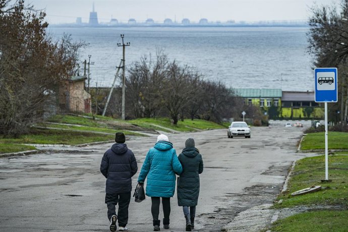 Archivo - Arquivo - Pessoas passeiam pela cidade de Nikopol, às margens do rio Dnieper, com a usina nuclear de Zaporiyia ao fundo.