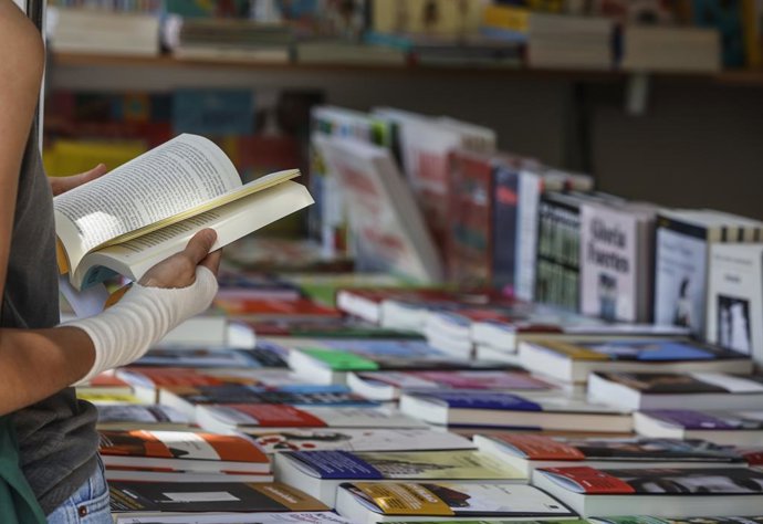 Archivo - Arxiu - Una persona subjecta un llibre en una de les casetes de la Fira del Llibre de València (arxiu)