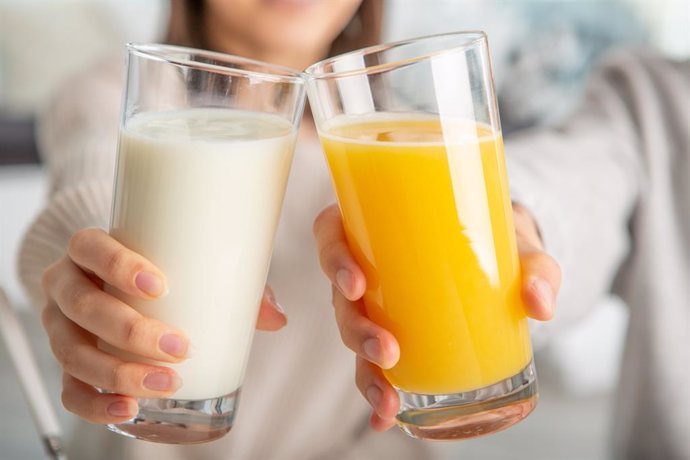 Archivo - Brindando con vaso de leche y vaso de zumo de naranja.