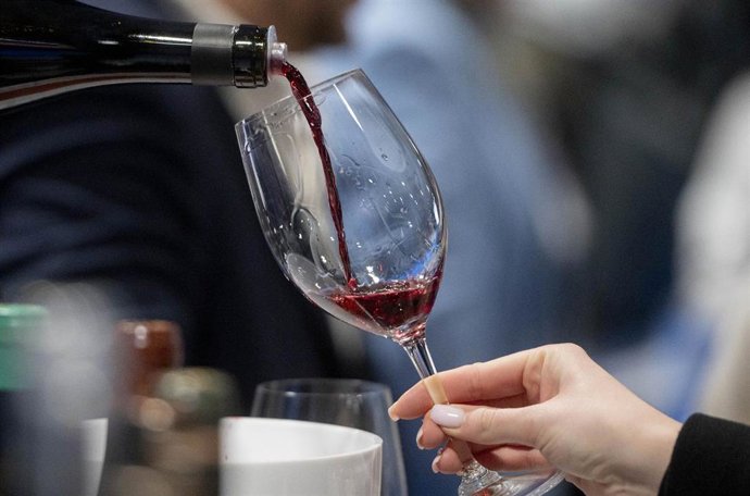 Una persona sirve una copa de vino 