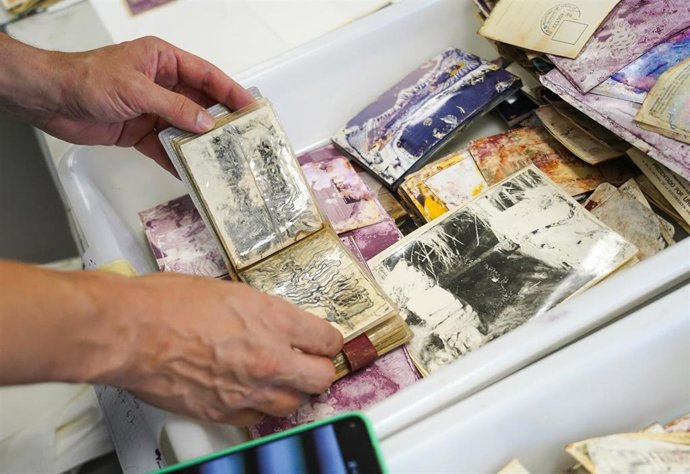 Archivo - Voluntarios  trabajan reparando fotografías familiares dañadas por la dana (archivo)
