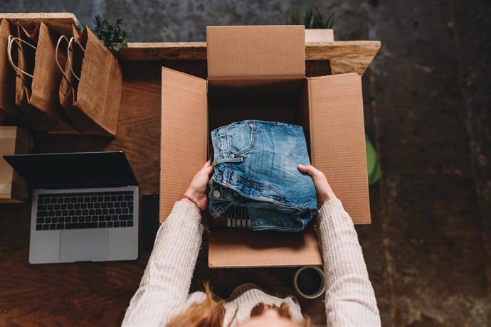Archivo - A millennial woman is preparing the shipment of some clothes in her new online shop. She's the owner of an online thrift store. New small business concept.