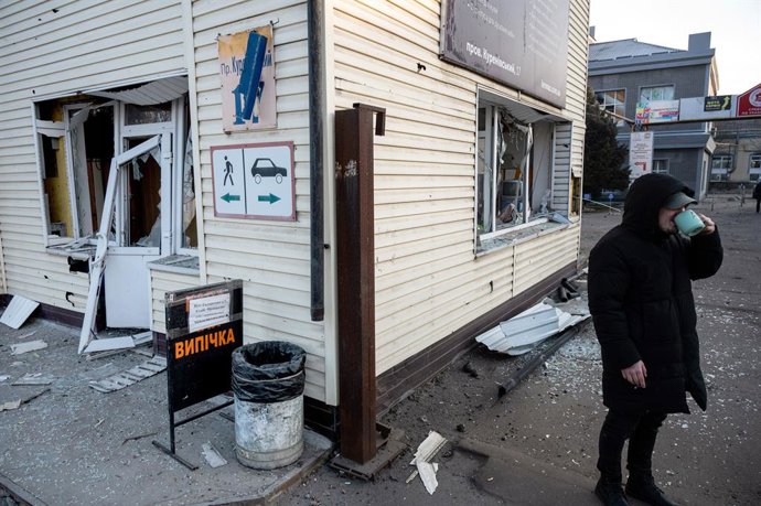 12 de fevereiro de 2025, Kiev, Ucrnia: KYIV, UCRNIA - 12 DE FEVEREIRO DE 2025 - Um homem bebe de um copo do lado de fora de um prédio no distrito de Obolonskyi danificado por um ataque de míssil balístico russo, em Kiev, capital da Ucrnia. Na madruga