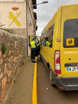 Un agente de la Guardia Civil junto al vehículo de transprte escolar interceptado en Alfambra (Teruel)