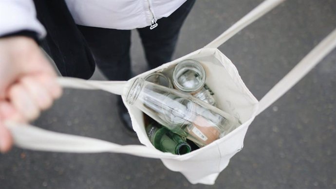 Archivo - Una persona muestra envases de vidrio para su reciclaje.