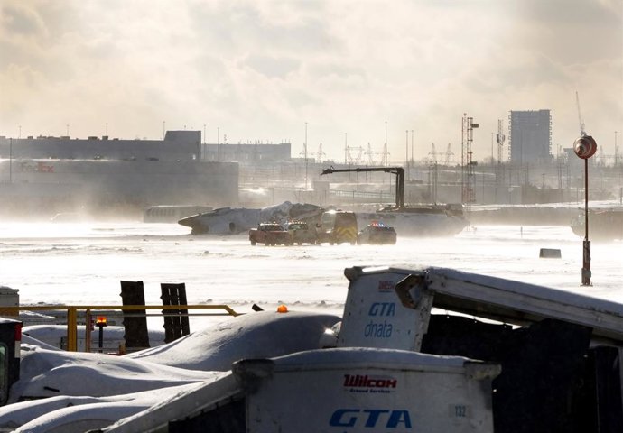 17 February 2025, Canada, Toronto: Emergency response vehicles are seen around an upside down Delta Air Lines plane on the tarmac at Toronto Pearson International airport.  