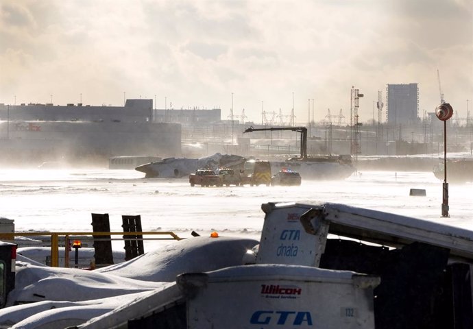 17 February 2025, Canada, Toronto: Emergency response vehicles are seen around an upside down Delta Air Lines plane on the tarmac at Toronto Pearson International airport.  A Delta Air Lines plane carrying 80 people crashed at a Canadian airport on Monday