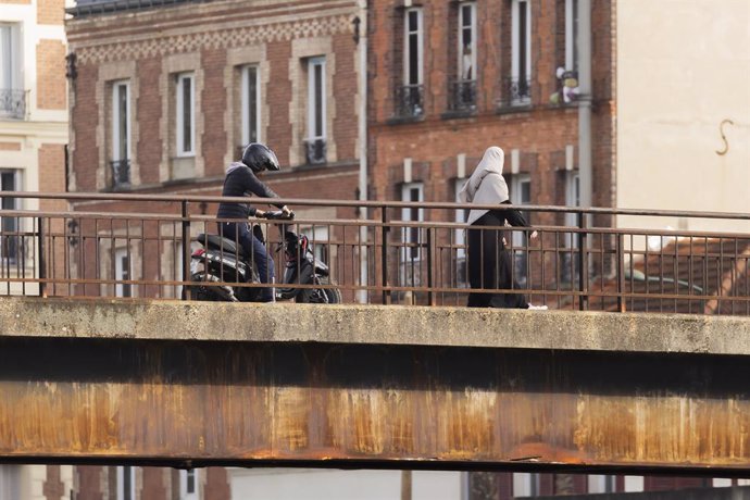 Archivo - February 15, 2024, Paris, France, France: Alfortville, France February 15, 2024 - A woman wearing a hijab and a young man on a scooter cross a bridge over the Marne river in the Paris region...ILLUSTRATION, JEUNES FRANCAIS ISSUS DE L IMMIGRATION