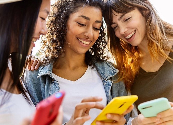 Três mulheres usando telefones celulares