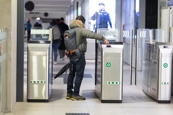 Una persona valida el seu bitllet en una estació de Rodalies