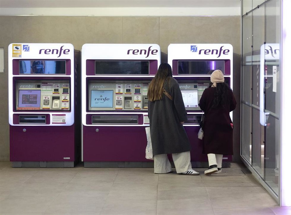 Varias personas compran billetes en una máquina de venta de billetes