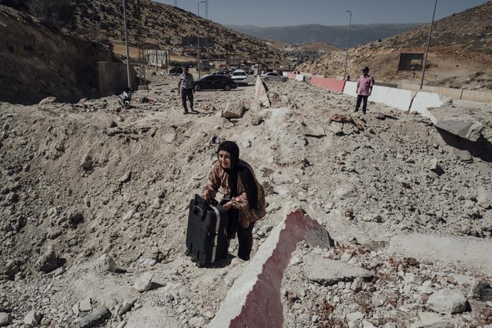 Archivo - Arquivo - 5 de outubro de 2024, Beirute, Beirute, Líbano: Uma mulher atravessa a cratera causada por bombardeios israelenses na estrada para a zona tampão entre o Líbano e a Síria.