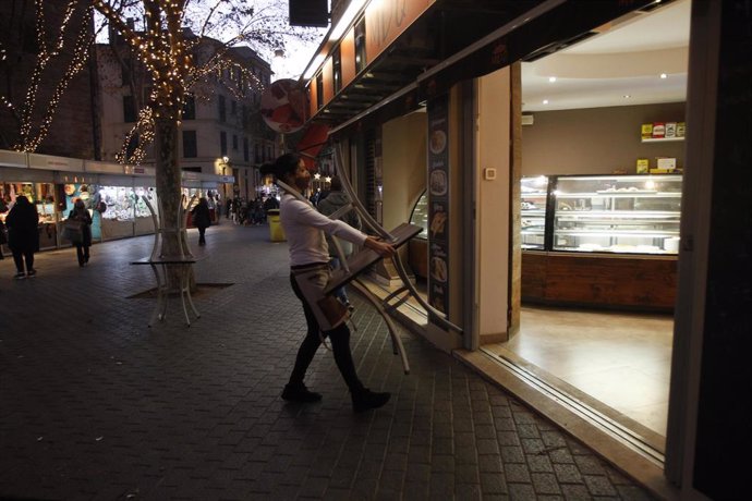 Archivo - Una camarera recoge las mesas de la terraza de una cafetería en Palma.