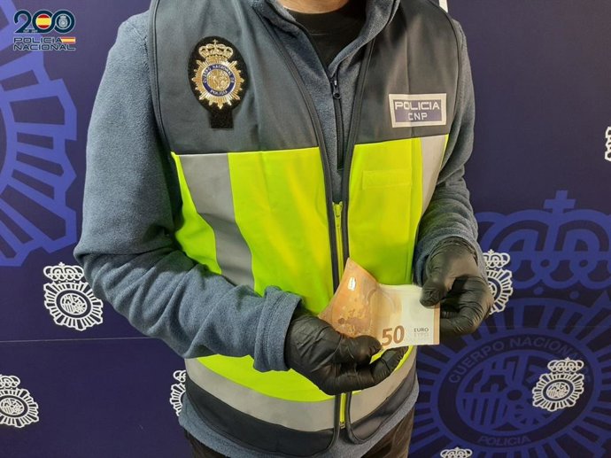 Un agente de la Policía Nacional muestra un billete de 50 euros falso intervenido