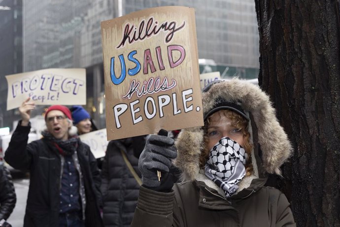 February 6, 2025, New York, New York, USA: A demonstrator holds a sign that reads 'Killing USAID Kills People.' outside the Manhattan offices of Senators Schumer and Gillibrand. In the rain constituents chant and hold signs demanding that the Democratic l