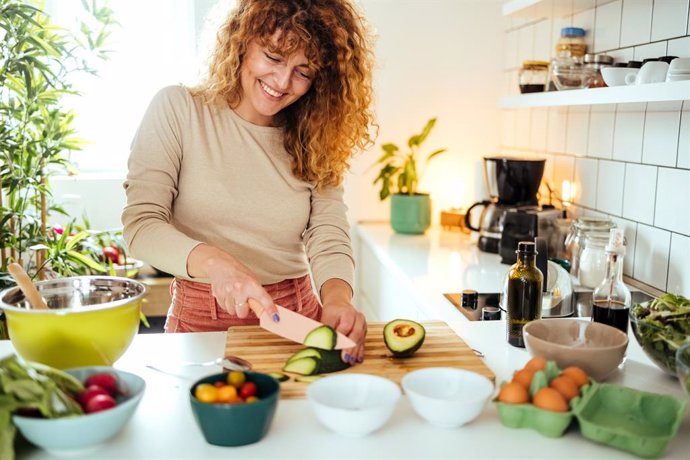 Archivo - Mujer cocinado una ensalada, con aguacate  y huevos.