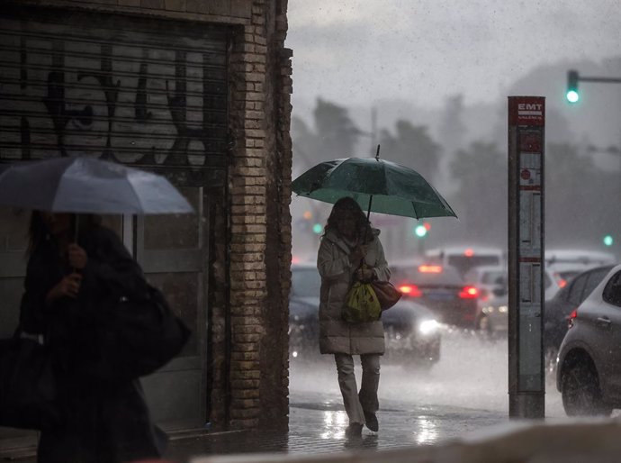 Archivo - Dos mujeres caminan mientras se protegen de la lluvia con paraguas, a 11 de noviembre de 2022, en Valencia, Comunidad Valenciana (España). La Agencia Estatal de Meteorología (Aemet) mantiene  el aviso de nivel amarillo por lluvias en el litoral 