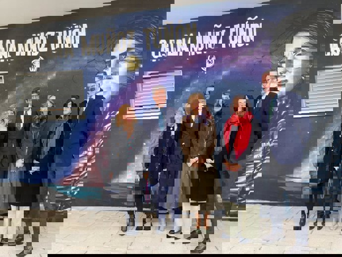 Casiana Muñoz Tuñón (2ª dcha.), con responsables de la Junta de Andalucía, ante un mural con su imagen en el instituto que lleva su nombre.