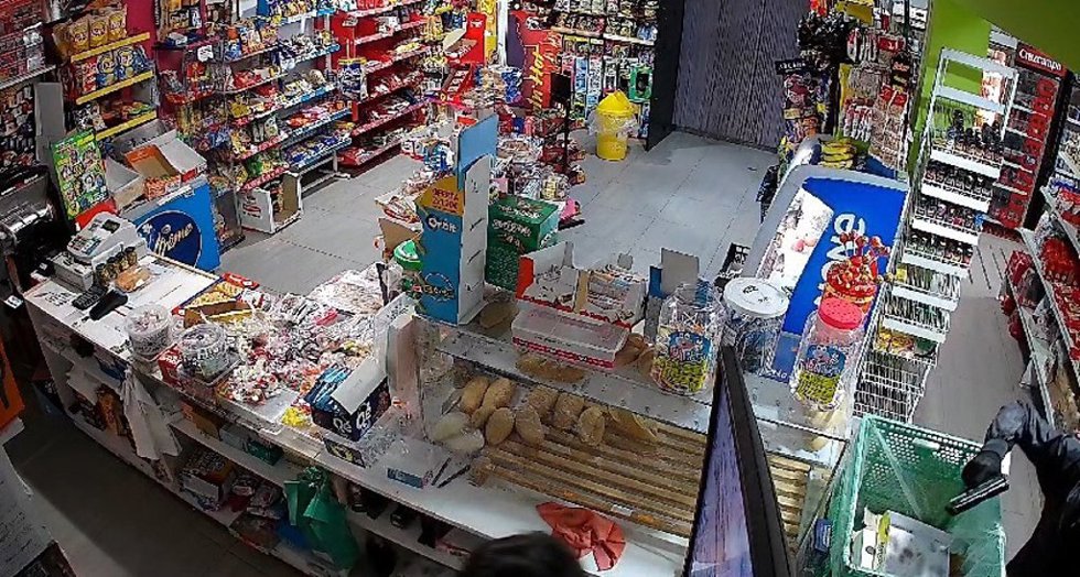 Imagen del momento del atraco, con el ladrón apuntando a la empleada del establecimiento con la pistola, en la esquina inferior derecha.