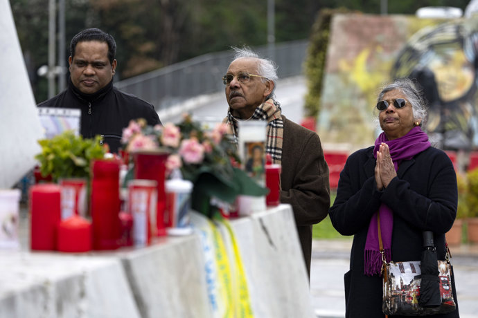 Tres personas rezan ante la estatua del Papa Juan Pablo II en el hospital Gemelli de Roma, donde el Papa Francisco está hospitalizado