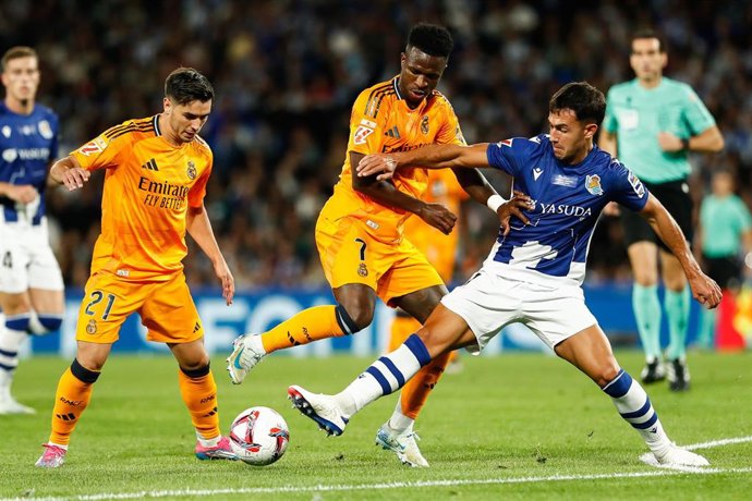 Archivo - Los jugadores del Real Madrid Brahim Díaz y Vinícius Júnior intentan regatear al centrocampista de la Real Sociedad Martin Zubimendi, en LaLiga EA Sports 2024-2025.