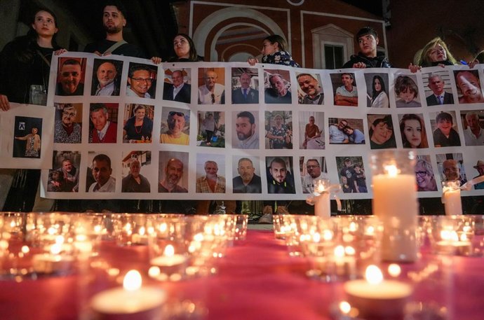 Várias pessoas seguram um cartaz com imagens de alguns dos mortos durante uma comemoração pelas vítimas do DANA em Valência, na Plaza de la Iglesia de Picanya, em 15 de fevereiro de 2025, em Picanya, Valência, Comunidade Valenciana (Espanha).