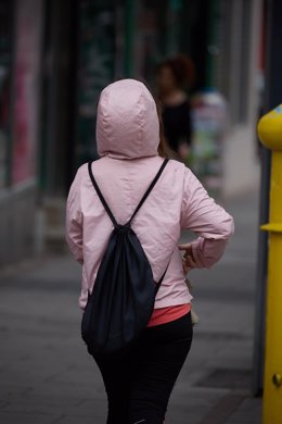 Archivo - Una persona se protege de la lluvia con una capucha